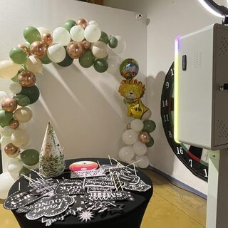 Coin photobooth décoré d’une arche de ballons avec accessoires posés sur une table
