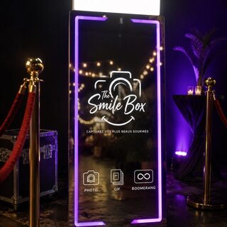 Miroirbooth The Smile Box éclairé en violet à l’entrée d’une soirée